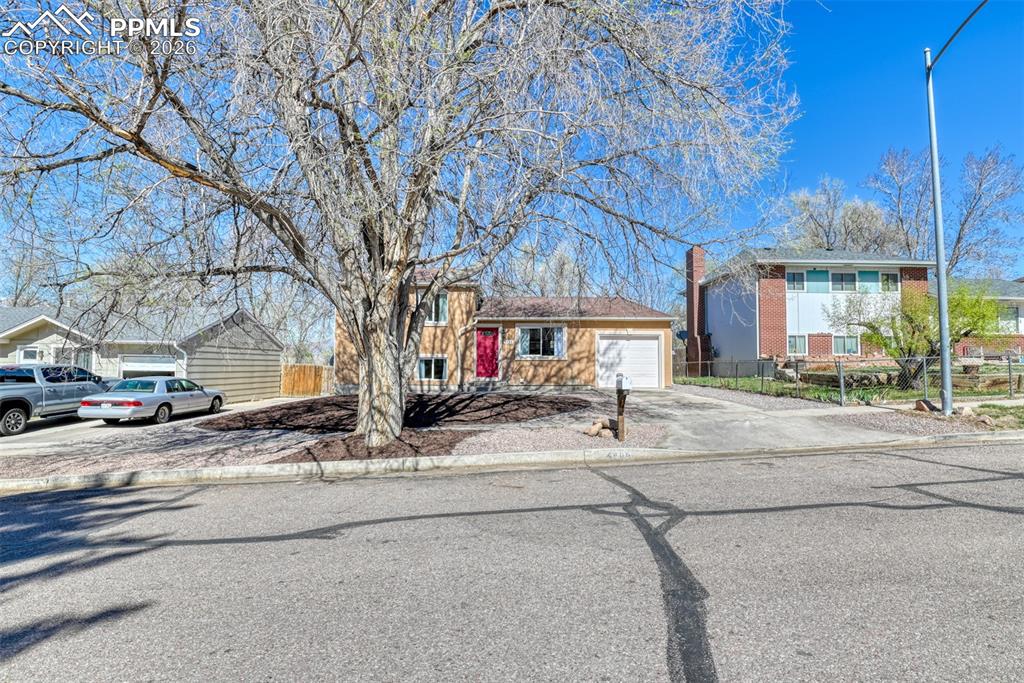 Image 2 of 39: The property features a single-car garage and a red front door, set back fr