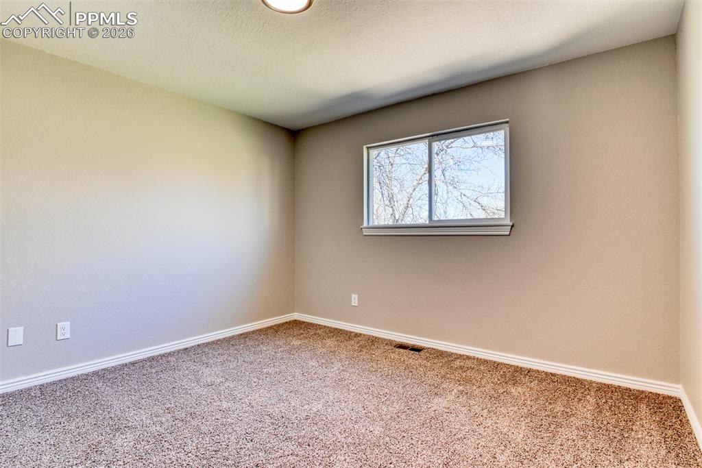 Image 22 of 39: This room features neutral-toned walls, a carpeted floor, and a window prov