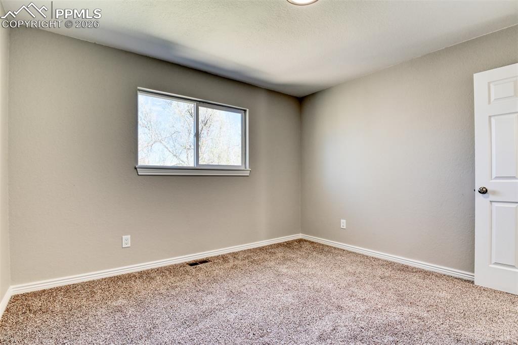 Image 25 of 39: Room with neutral-toned walls, carpeted flooring, and a window providing na
