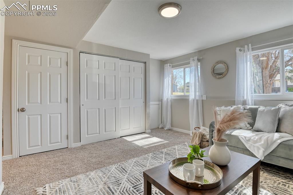 Image 27 of 39: This living space features a neutral color palette, carpeted flooring, and
