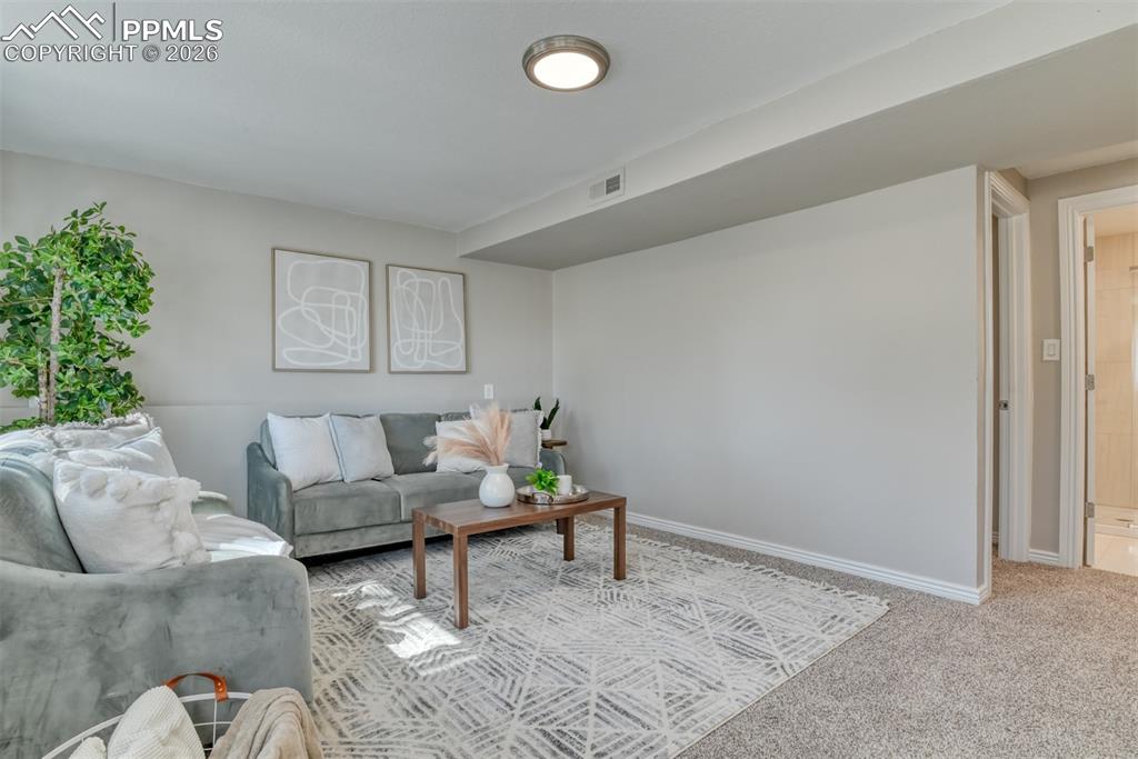 Image 29 of 39: The living area features light-colored walls, carpeted flooring, and a flus