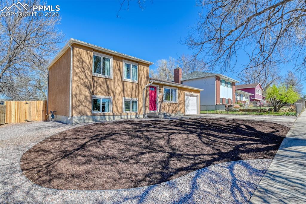 Image 3 of 39: The property features a stucco exterior with a striking red entry door, a s
