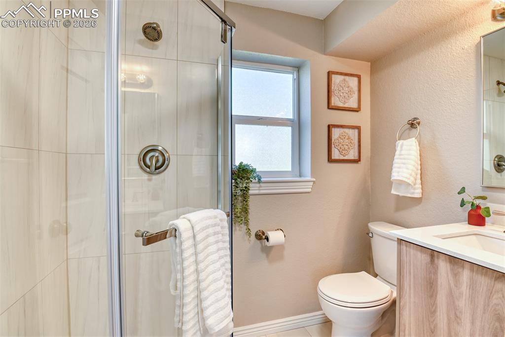 Image 30 of 39: The bathroom features a glass-enclosed shower with tiled walls and a brushe
