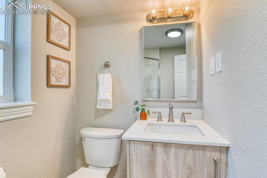 Image 31 of 39: Bathroom featuring a vanity with a light wood-grain cabinet, a white counte