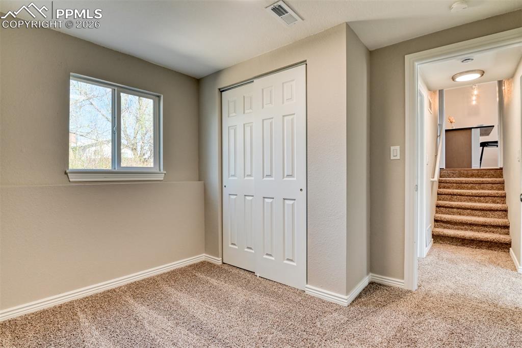 Image 33 of 39: This room features carpeted flooring, a window offering natural light, and