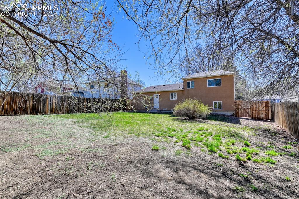 Image 36 of 39: The property features a spacious rear yard with a perimeter fence, a sloped
