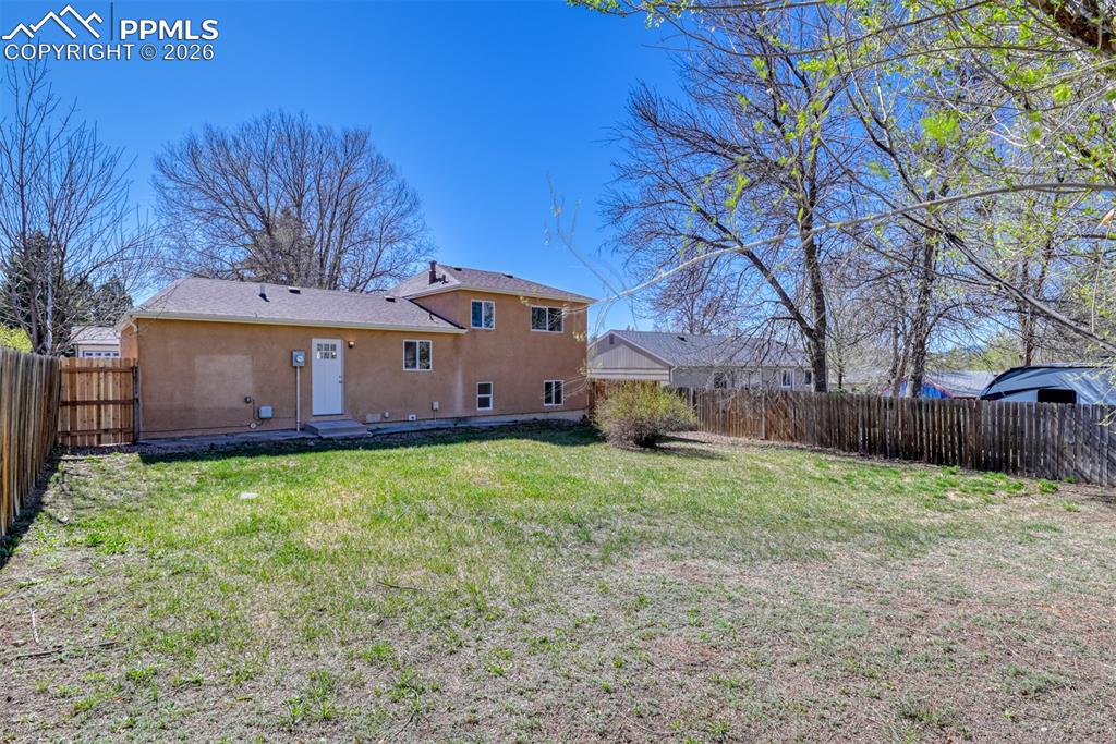 Image 37 of 39: The property features a private yard with a wooden fence and a lawn area