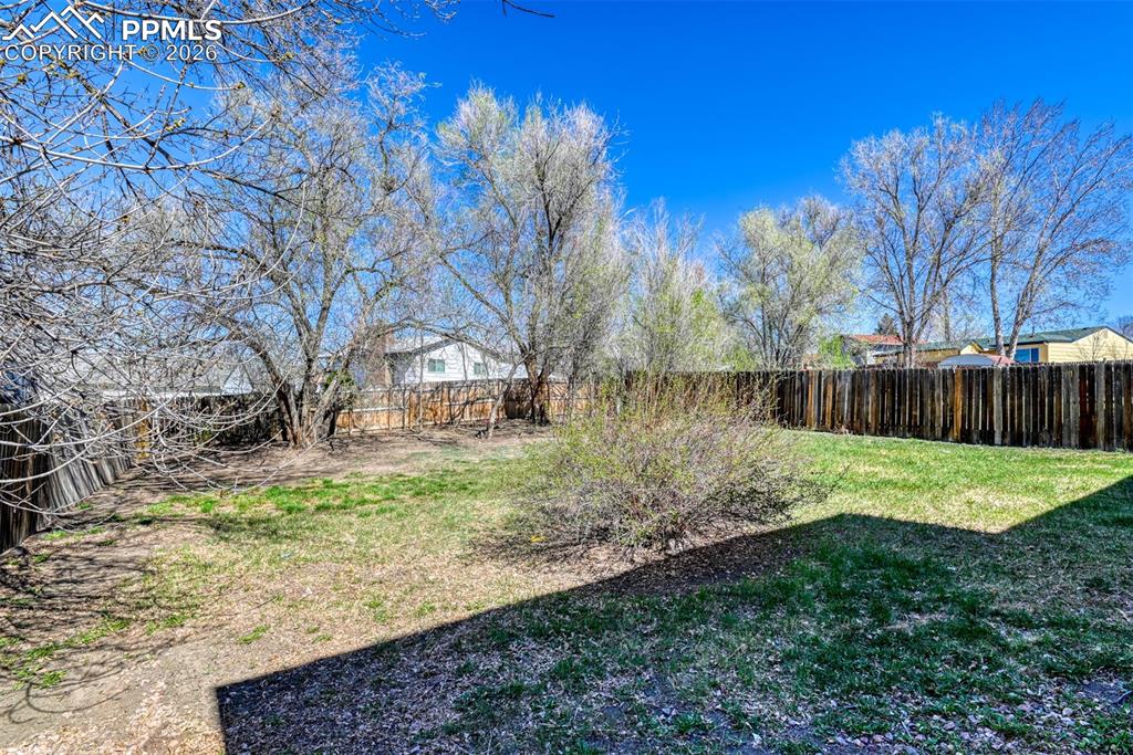 Image 38 of 39: The property features a fenced yard with mature trees and a lawn area