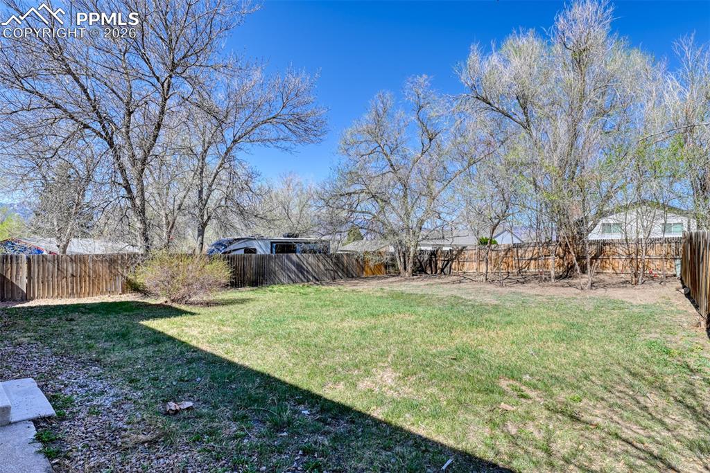 Image 39 of 39: The property features an extensive backyard with a grassy lawn, mature tree