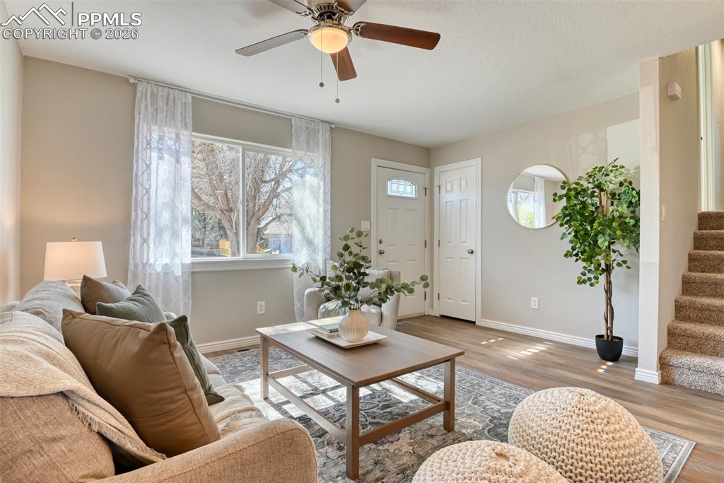 Image 7 of 39: Inviting living area featuring light-toned walls, a ceiling fan, and durabl