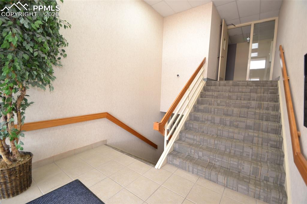 Image 5 of 16: Stairway with a paneled ceiling and tile patterned floors