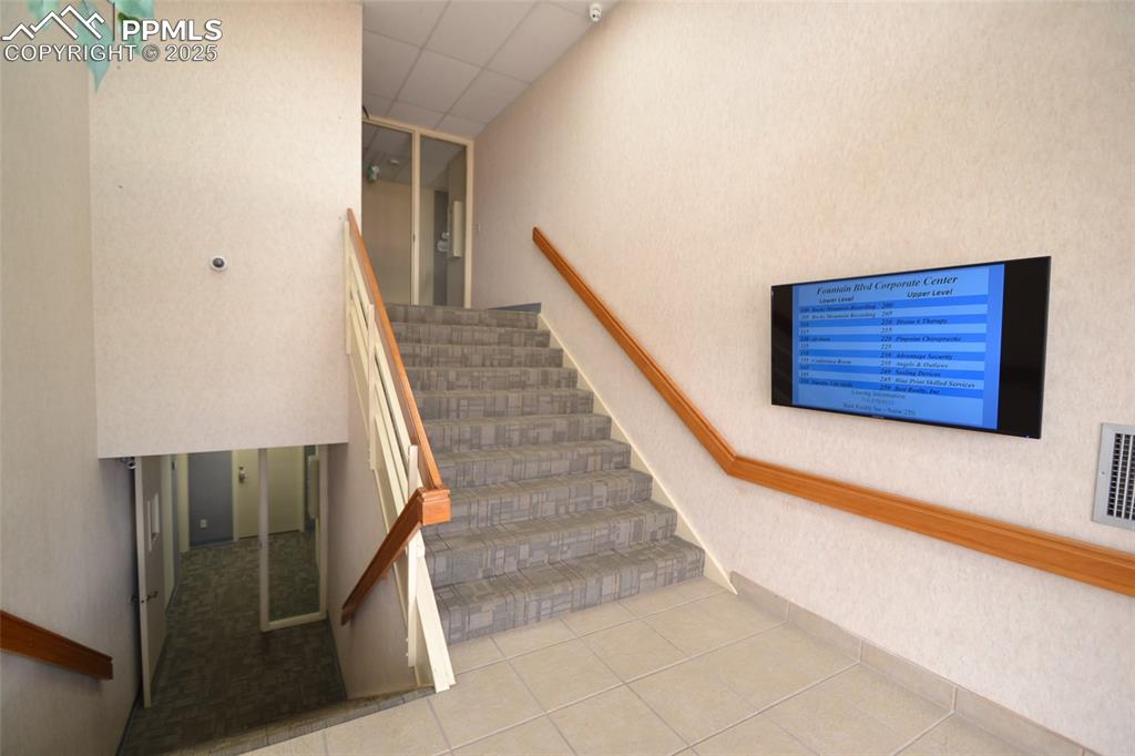 Image 7 of 16: Stairway with a paneled ceiling and tile patterned floors