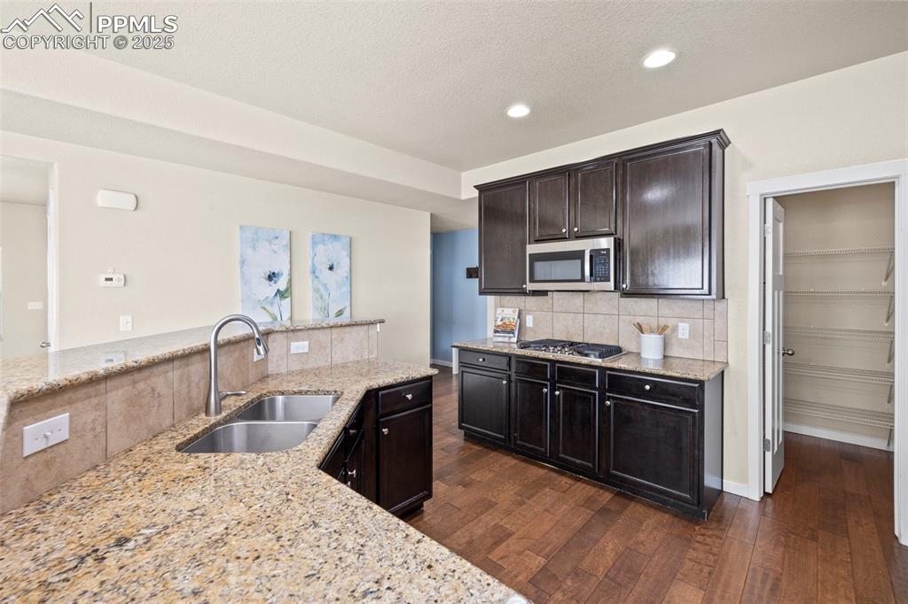 Image 11 of 31: Kitchen with appliances with stainless steel finishes, dark wood-style floo