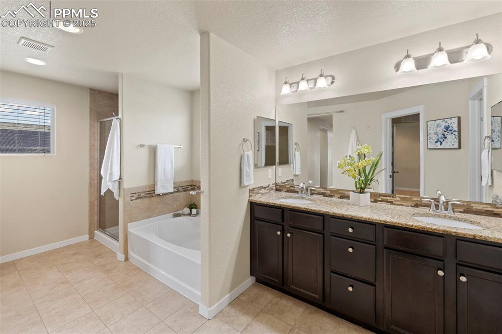 Image 18 of 31: Full bath with a soaking tub, double vanity, and stand alone shower 