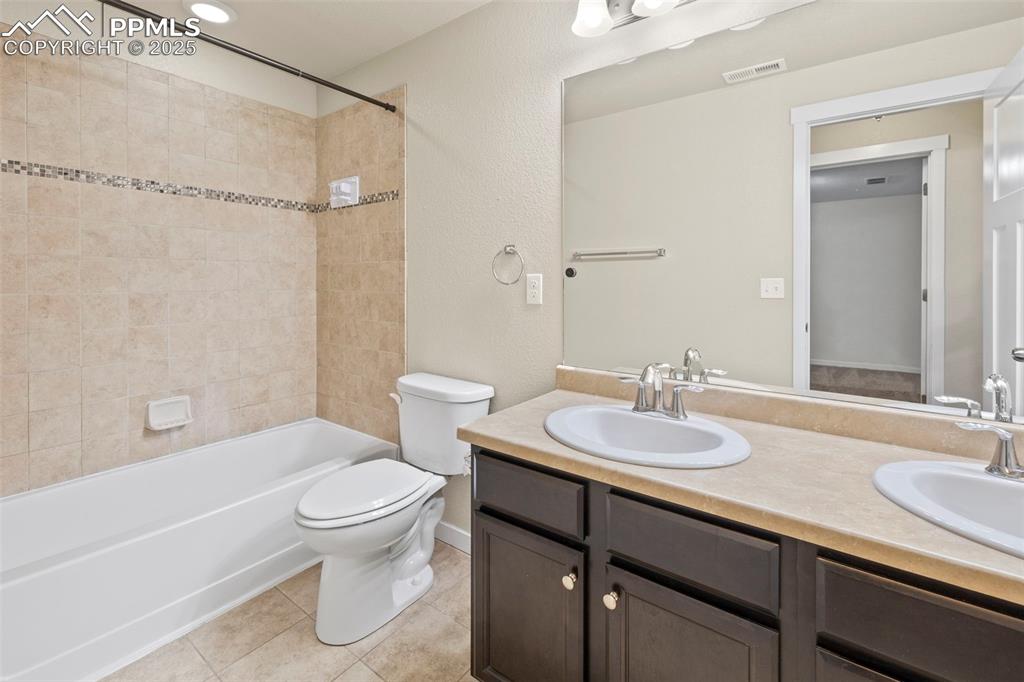 Image 28 of 31: Basement bathroom with double vanity and shower/tub