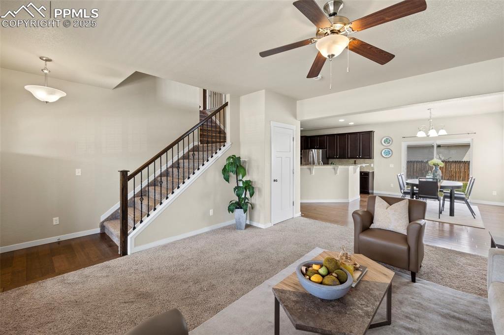 Image 7 of 31: Living room featuring stairs, a ceiling fan, a chandelier, and wood finishe