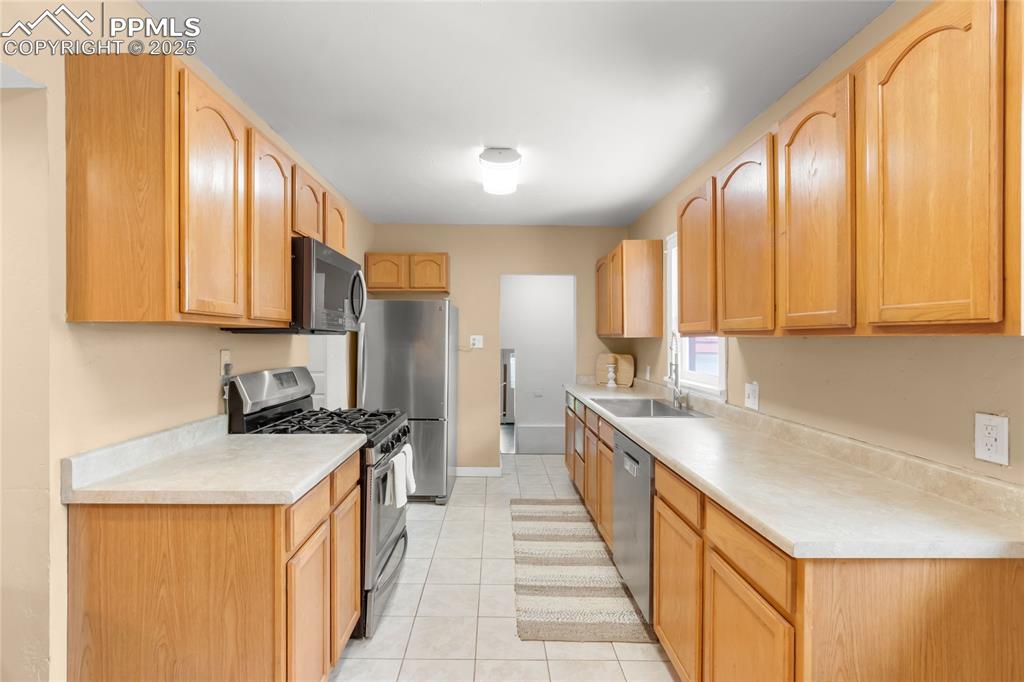 Image 10 of 39: Kitchen featuring stainless steel appliances, light countertops, light tile