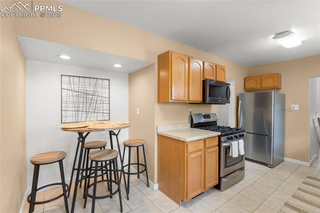 Image 11 of 39: Kitchen with appliances with stainless steel finishes, light countertops, l