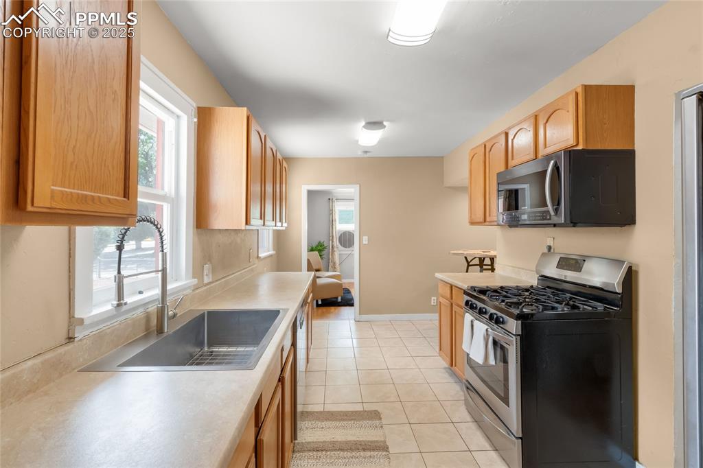 Image 14 of 39: Kitchen with gas stove, light countertops, light tile patterned flooring, a