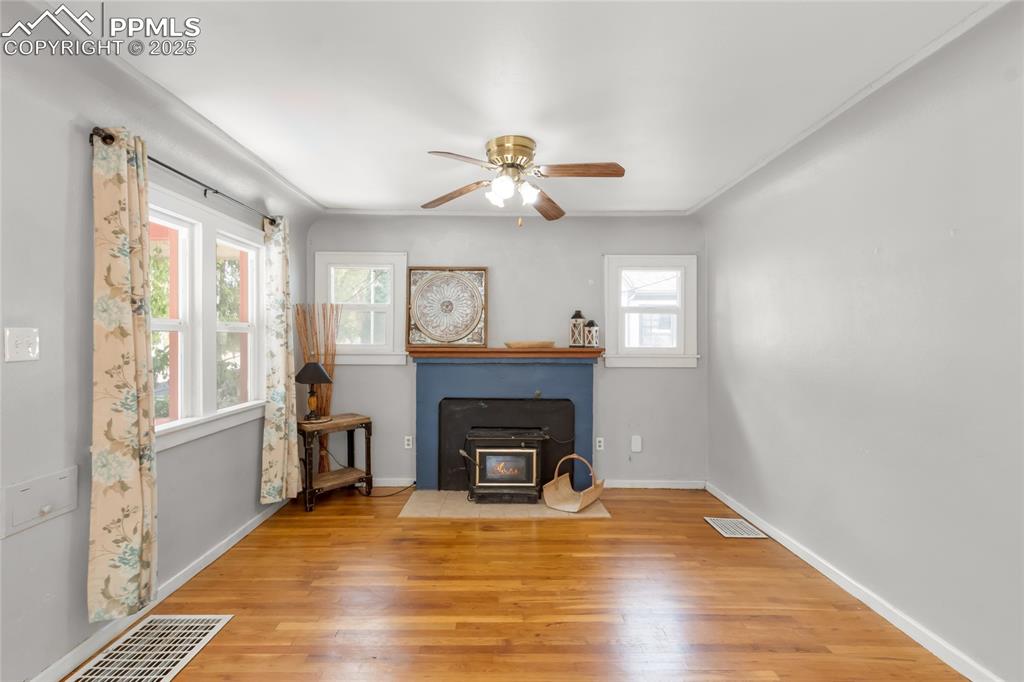 Image 4 of 39: Living area featuring a wood stove, ceiling fan, and wood finished floors