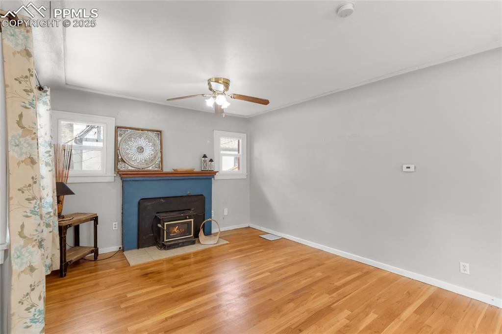 Image 8 of 39: Unfurnished living room featuring a wood stove, ceiling fan, and wood finis