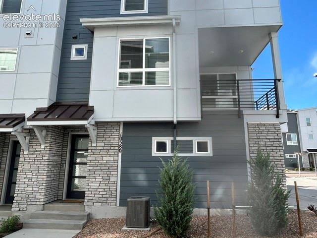 Image 1 of 24: Modern townhome exterior featuring stone veneer, blue horizontal siding, an