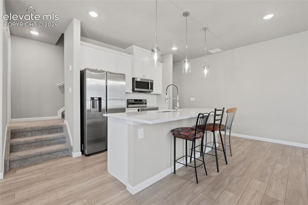 Image 13 of 24: Kitchen featuring an island with breakfast bar and pendant lighting