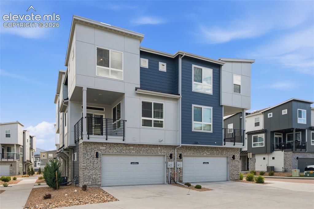 Image 23 of 24: Contemporary multi-level townhome featuring stone and panel exterior, an u