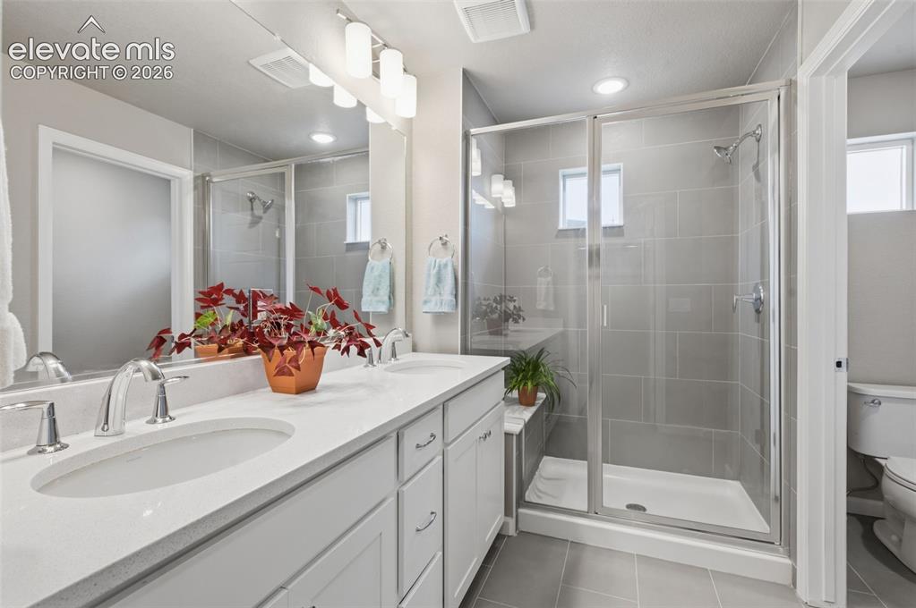 Image 4 of 24: Primary bathroom has double vanity, tile floor and step-in shower