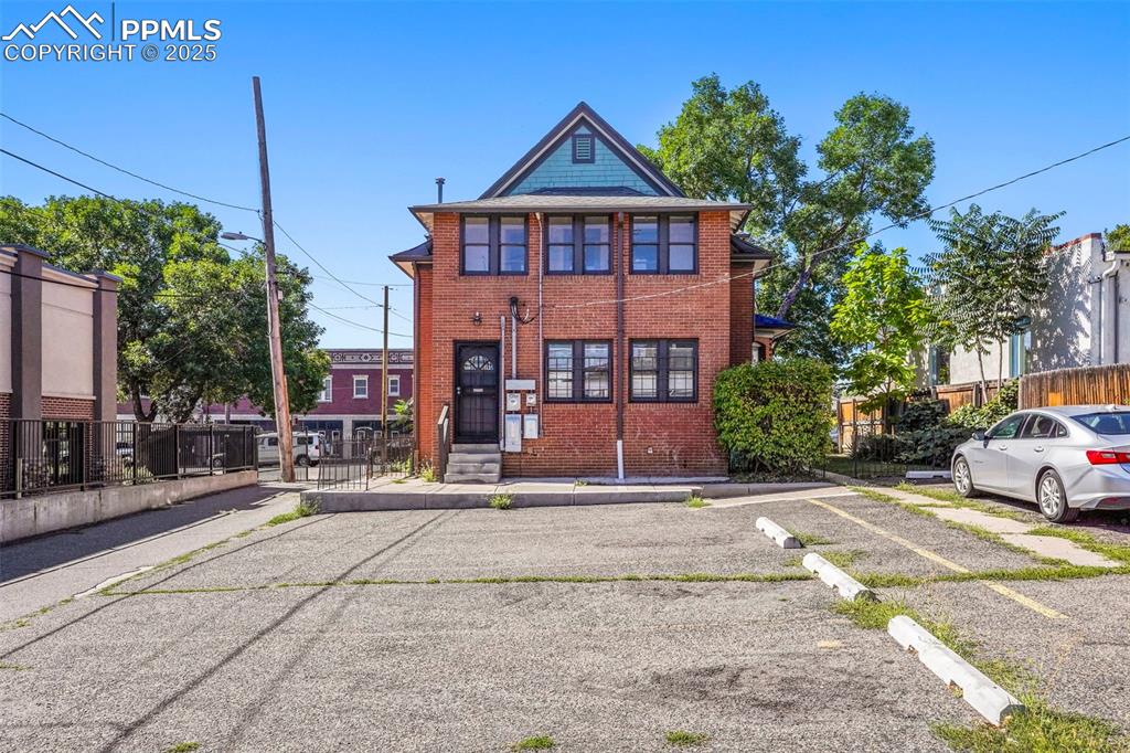 Image 3 of 28: View of front of property with uncovered parking and brick siding