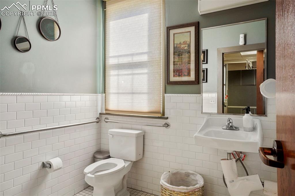 Image 9 of 28: Bathroom with tile walls, a wainscoted wall, and tile patterned flooring