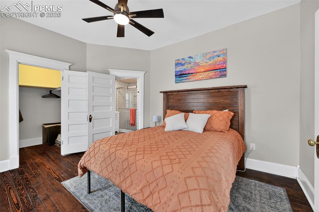 Image 13 of 34: Large primary bedroom with wood flooring, ceiling fan, large walk-in closet