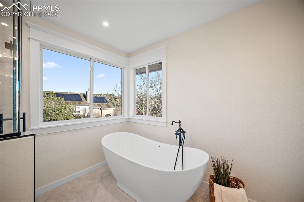 Image 26 of 50: Primary bath featuring a luxurious soaking tub and view