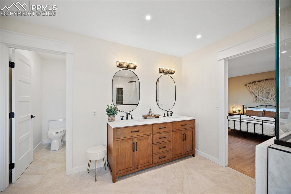 Image 27 of 50: Primary bathroom featuring double vanity, ensuite bathroom, and recessed li
