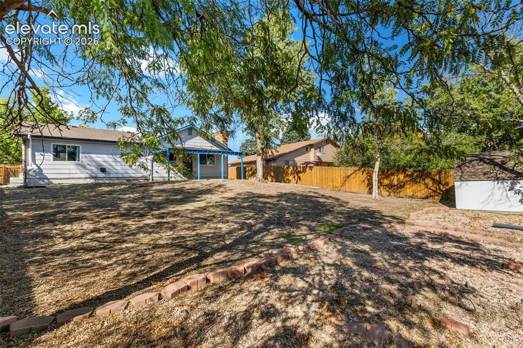 Image 21 of 27: Expansive outdoor space featuring a sloped grade, established trees, and a