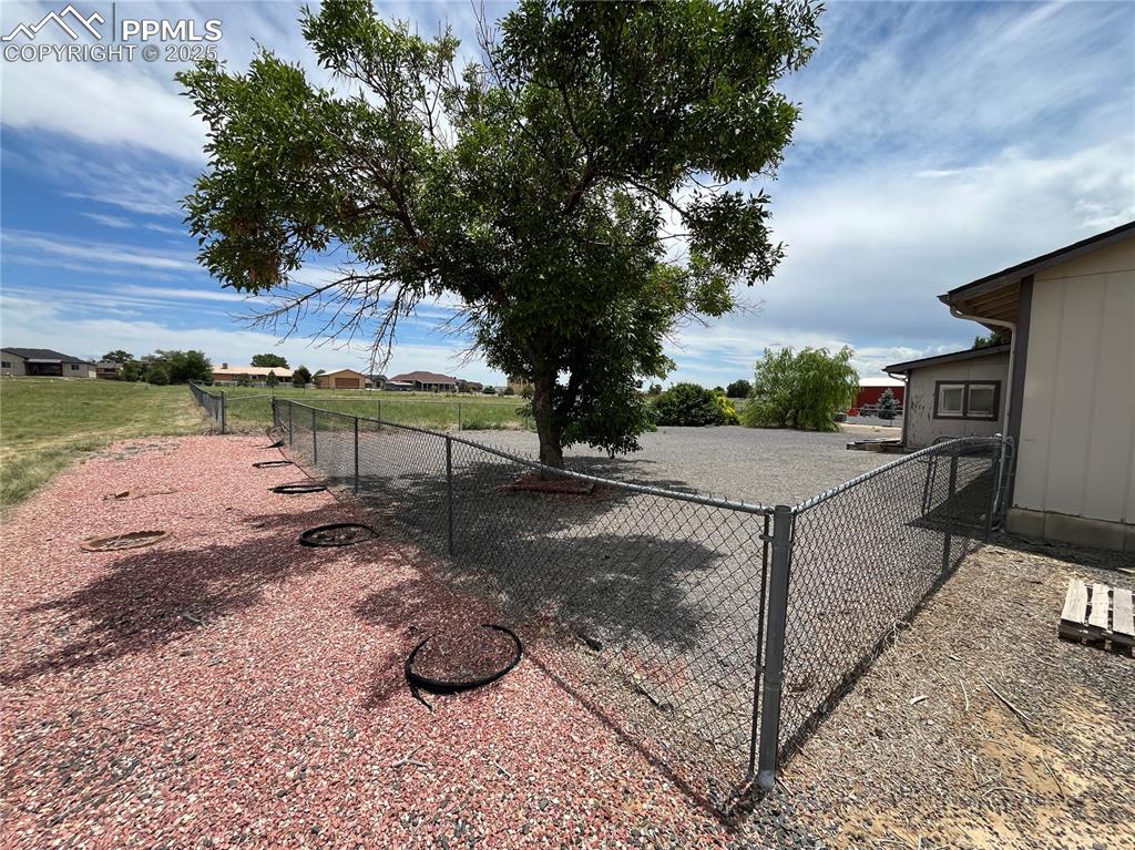 Image 4 of 21: Fenced xeriscaped yard with mature trees.