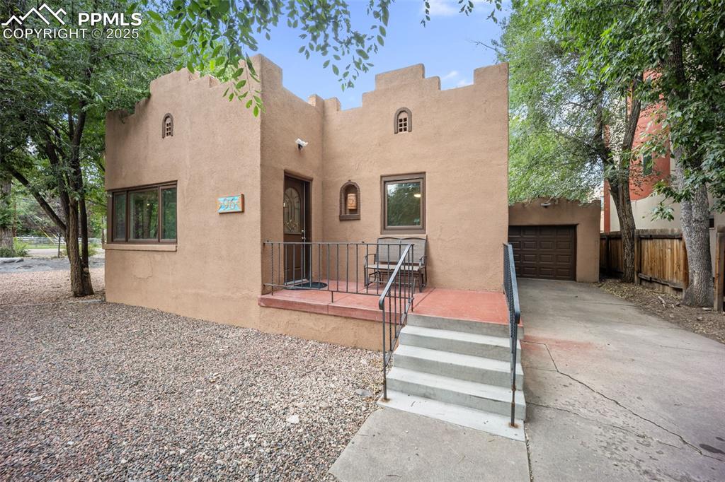Caption: View of front of property featuring a garage, stucco siding, and concrete driveway