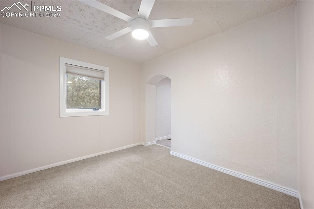 Image 18 of 31: Empty room featuring arched walkways, carpet floors, a ceiling fan, and a t