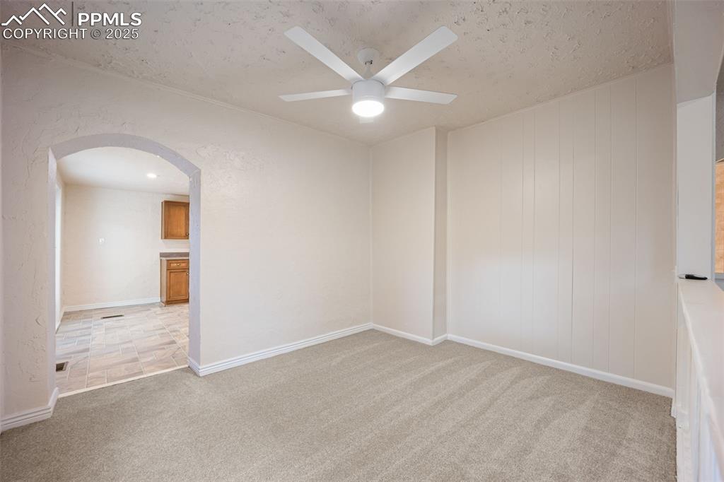 Image 24 of 31: Unfurnished room featuring arched walkways, light carpet, ceiling fan, and