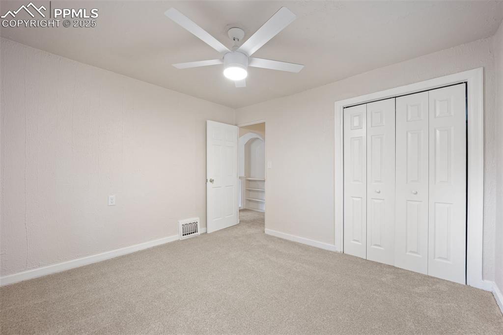 Image 28 of 31: Unfurnished bedroom featuring carpet flooring, arched walkways, a closet, a