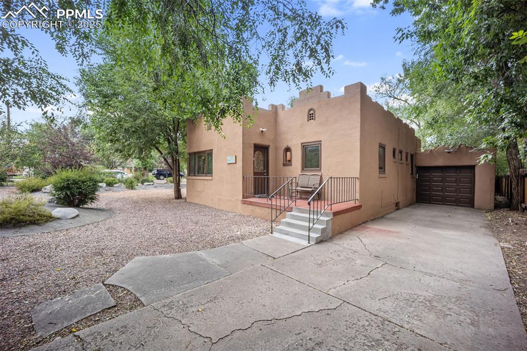 Image 3 of 31: Adobe home with stucco siding, driveway, and an attached garage
