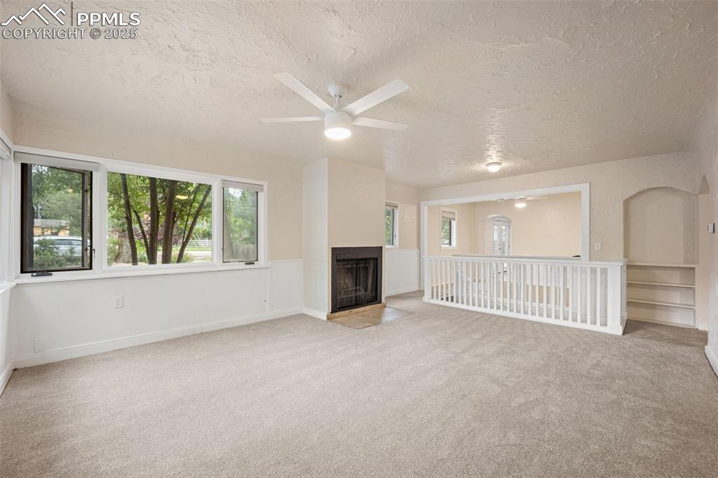 Image 5 of 31: Unfurnished living room featuring a textured ceiling, a ceiling fan, light