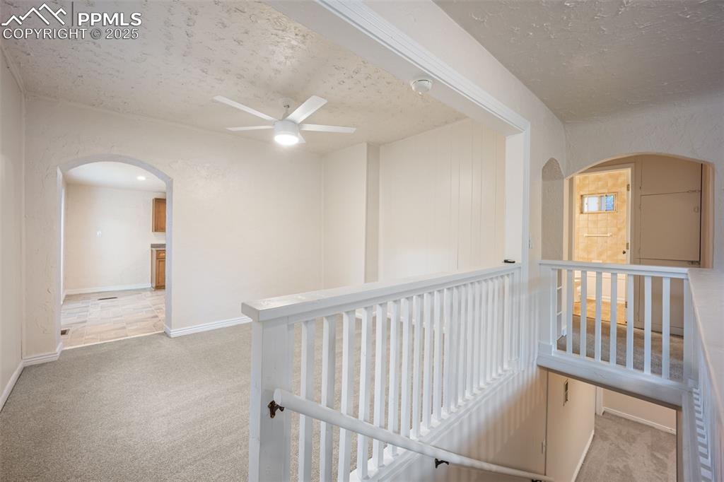 Image 9 of 31: Hall featuring arched walkways, carpet floors, a textured ceiling, and an u