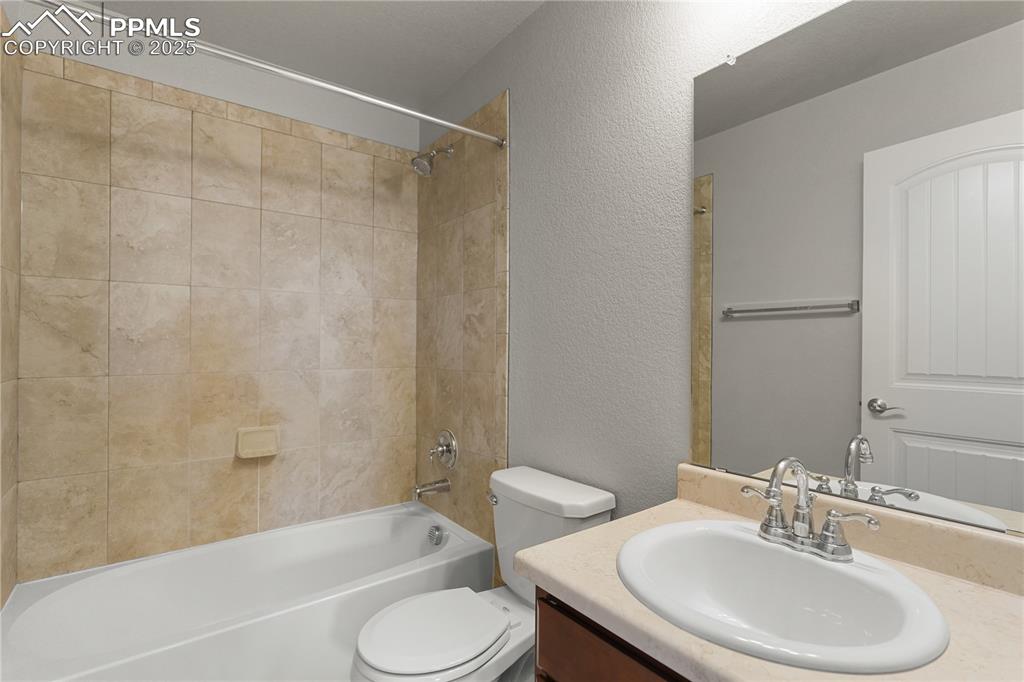 Image 11 of 22: Bathroom featuring a textured wall, vanity, and shower / bathtub combinatio
