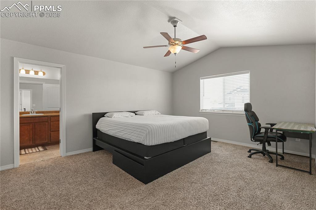 Image 16 of 22: Bedroom featuring light colored carpet, lofted ceiling, connected bathroom,