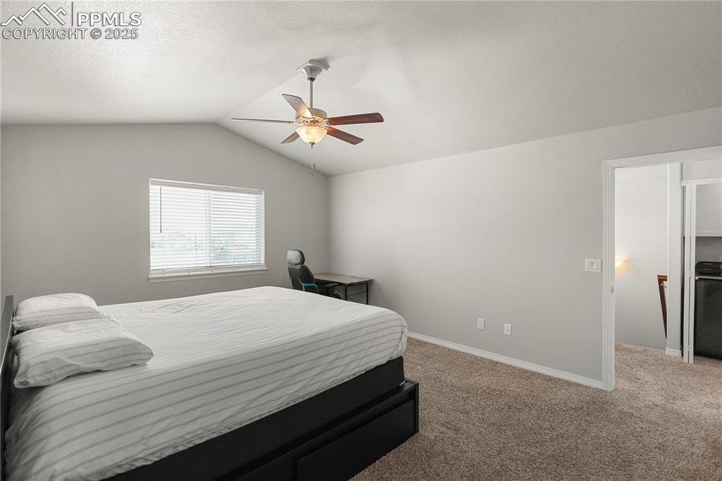 Image 17 of 22: Bedroom with light carpet, vaulted ceiling, and a ceiling fan