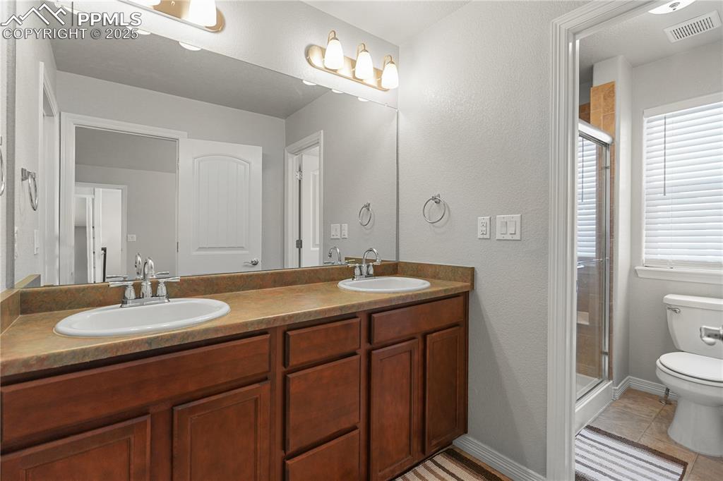 Image 18 of 22: Full bathroom featuring a stall shower, double vanity, and tile patterned f