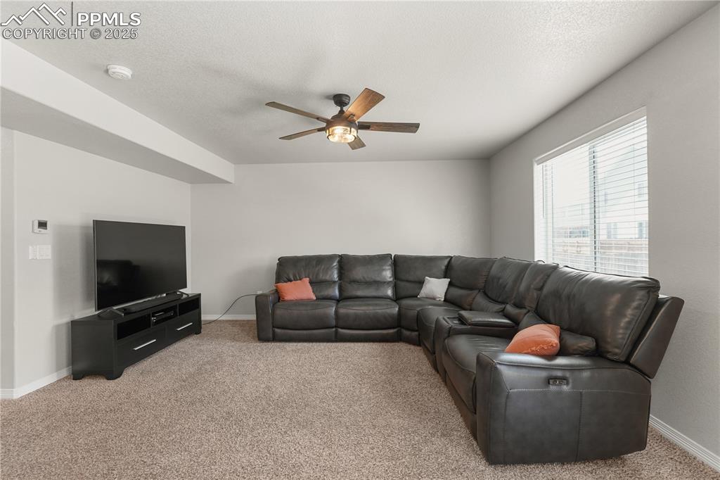 Image 6 of 22: Living area with carpet flooring, a ceiling fan, and a textured ceiling
