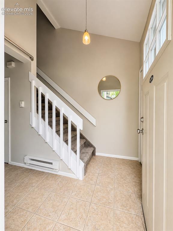 Image 11 of 27: Tiled entry foyer featuring a carpeted staircase with white railings, a pen