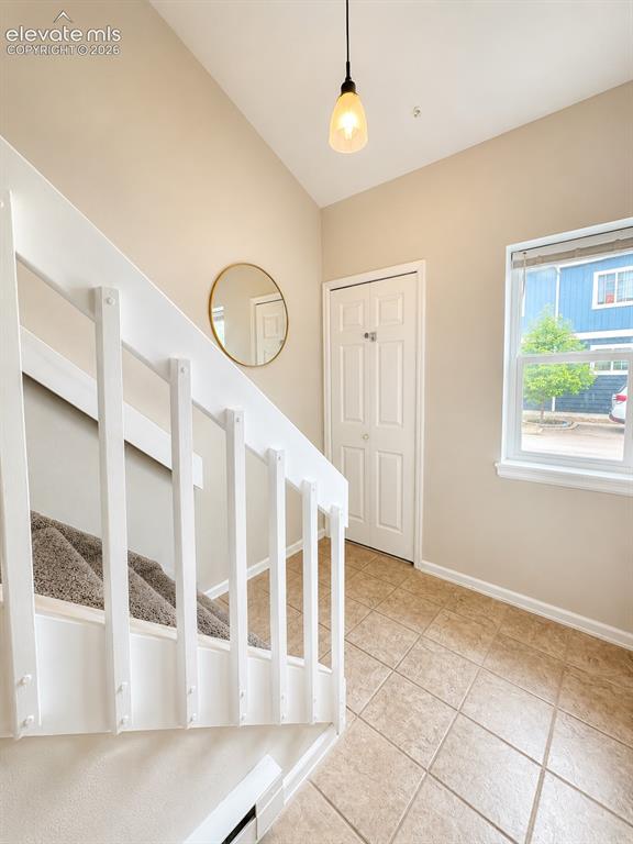 Image 12 of 27: Foyer featuring tiled flooring, a prominent staircase with white railings, 